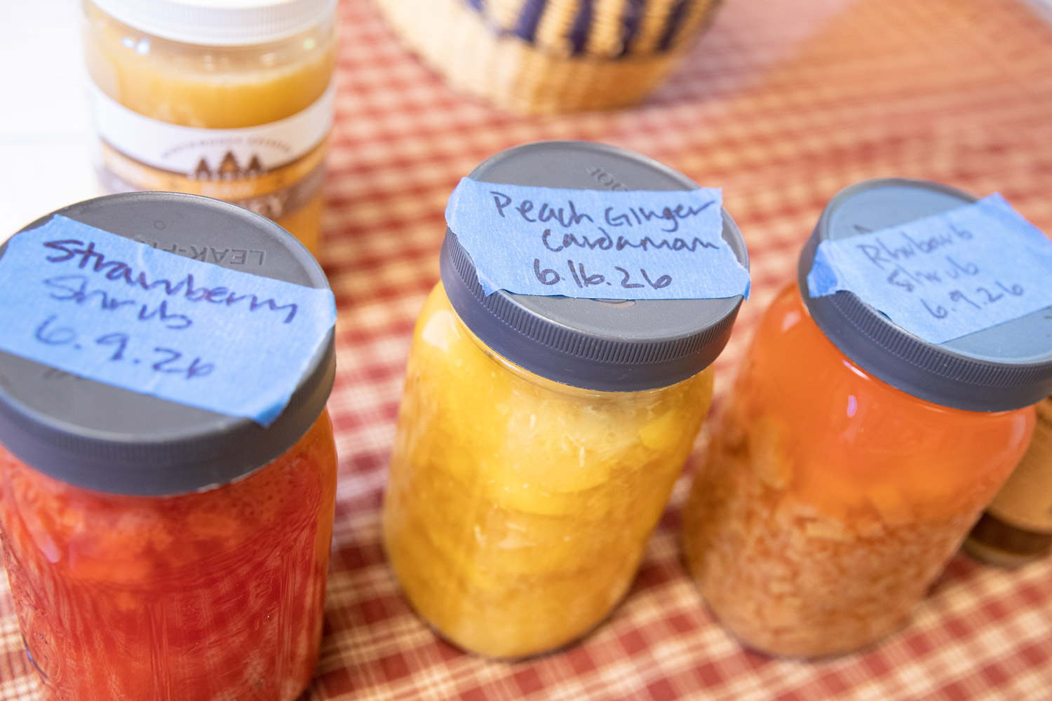 Jars of shrubs are labeled with dates and flavors: strawberry shrub, peach ginger cardamom, and rhubarb shrub.